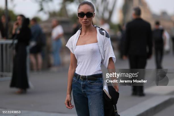 Adwoa Aboah is seen wearing Chanel sunnies, white tank top, tied over white shirt, black leather belt, blue pair of jeans, red leather loafers and...