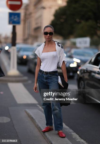 Adwoa Aboah is seen wearing Chanel sunnies, white tank top, tied over white shirt, black leather belt, blue pair of jeans, red leather loafers and...