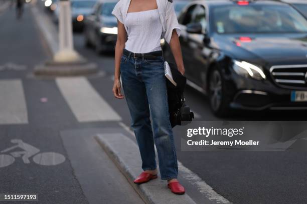 Adwoa Aboah is seen wearing Chanel sunnies, white tank top, tied over white shirt, black leather belt, blue pair of jeans, red leather loafers and...