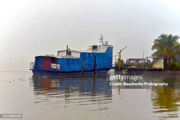 blue cargo boat known as tongkang moored at the river bank on a foggy morning - sibu river stock pictures, royalty-free photos & images