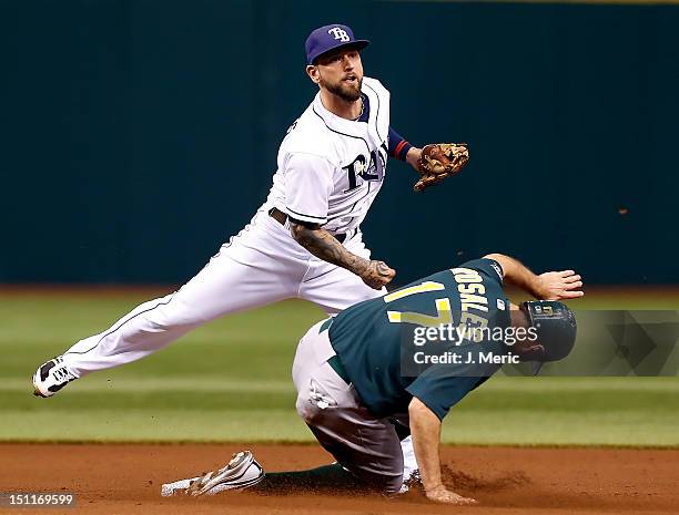 Infielder Ryan Roberts of the Tampa Bay Rays turns a double play as Adam Rosales of the Oakland Athletics tries to break it up during the game at...