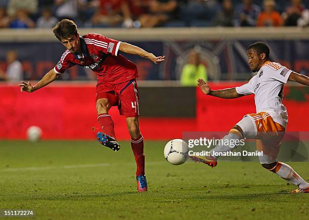 Alvaro Fernandez of the Chicago Fire shoots against Corey Ashe of the Houston Dynamo during an MLS match at Toyota Park on September 2, 2012 in...
