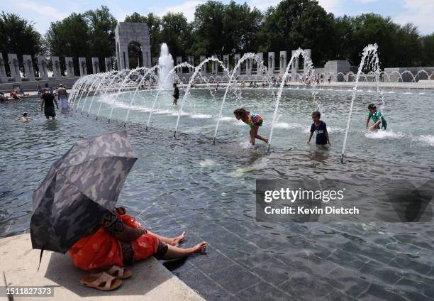 Visitors and tourists to the World War II Memorial seek relief from the hot weather in the memorial's fountain on July 03, 2023 in Washington, DC....