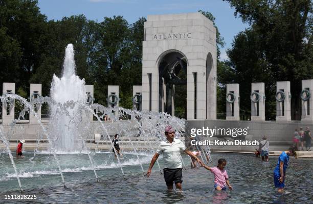 Visitors and tourists to the World War II Memorial seek relief from the hot weather in the memorial's fountain on July 03, 2023 in Washington, DC....