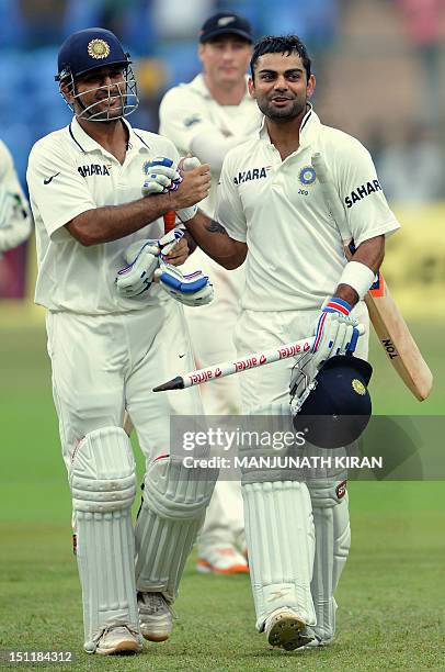 Indian batsman Virat Kohli and captain Mahendra Singh Dhoni celebrate after India won the second Test match against New Zealand at the M. Chinnaswamy...