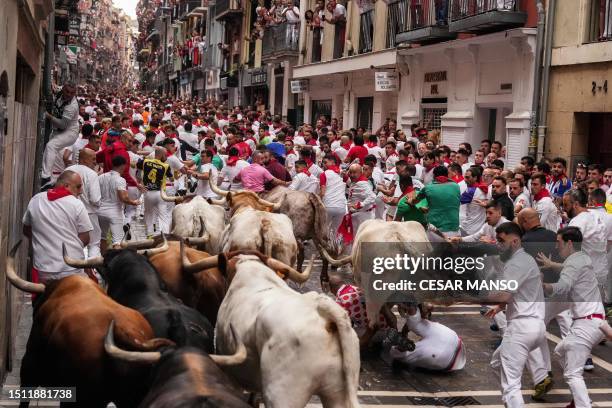 Participants fall down as they run with bulls during the first "encierro" of the San Fermin festival in Pamplona, northern Spain, on July 7, 2023....