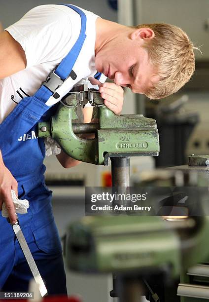 Trainee files a piece of metal at a Siemens training center on September 3, 2012 in Berlin, Germany. Nearly 400 trainees began their apprenticeship...