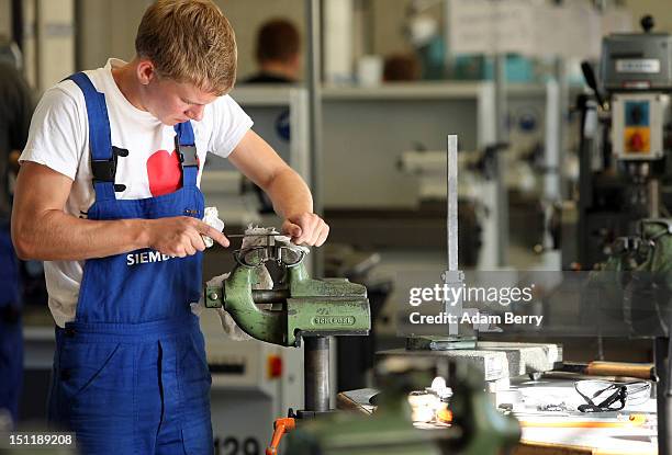 Trainee files a piece of metal at a Siemens training center on September 3, 2012 in Berlin, Germany. Nearly 400 trainees began their apprenticeship...