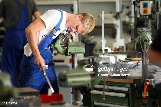 Trainee files a piece of metal at a Siemens training center on September 3, 2012 in Berlin, Germany. Nearly 400 trainees began their apprenticeship...