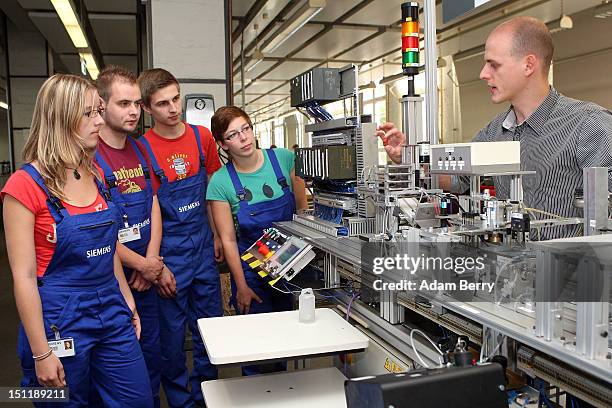 Instructor Bjoern Weiss explains the gear sorting line to new trainees at a Siemens training center on September 3, 2012 in Berlin, Germany. Nearly...