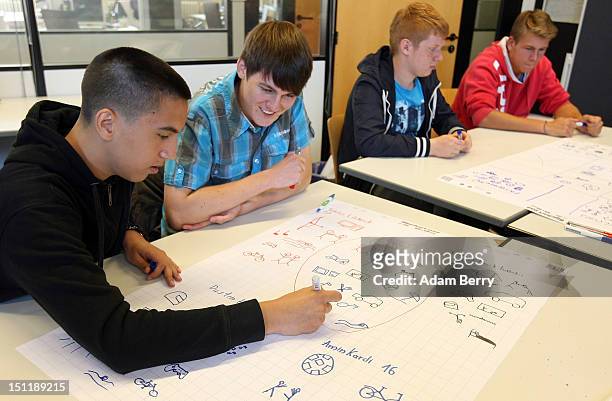 New trainees write their names and draw pictures of their interests on their first day at a Siemens training center on September 3, 2012 in Berlin,...