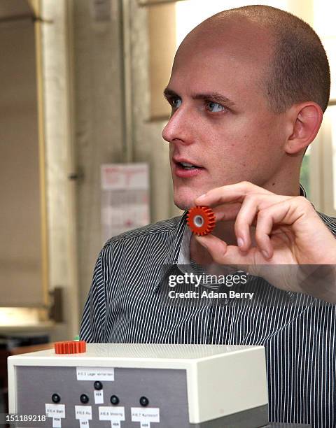 Instructor Bjoern Weiss explains the gear sorting line to new trainees at a Siemens training center on September 3, 2012 in Berlin, Germany. Nearly...