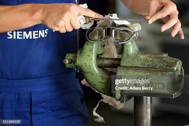 Trainee files a piece of metal at a Siemens training center on September 3, 2012 in Berlin, Germany. Nearly 400 trainees began their apprenticeship...