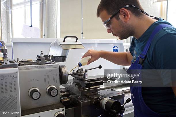 Trainee lubricates a turning machine at a Siemens training center on September 3, 2012 in Berlin, Germany. Nearly 400 trainees began their...