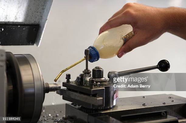Trainee lubricates a turning machine at a Siemens training center on September 3, 2012 in Berlin, Germany. Nearly 400 trainees began their...