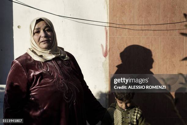 Syrian woman stands next to a boy after his father was shot by an army sniper in Al-Qsair, 25kms southwest of the flashpoint city Homs, on January...