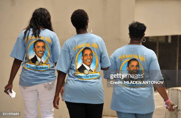 Three women wear T-shirts with pictures of US President Barack Obama stating, "He saved our jobs" as they walk outside the Time Warner Arena where...