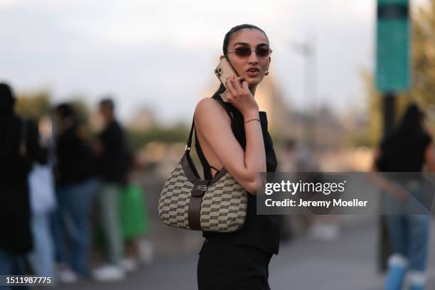 July 02: Guest is seen wearing black top, black shorts, Balenciaga logo shoulder bag and black loafers outside Alaia show during the Haute Couture...