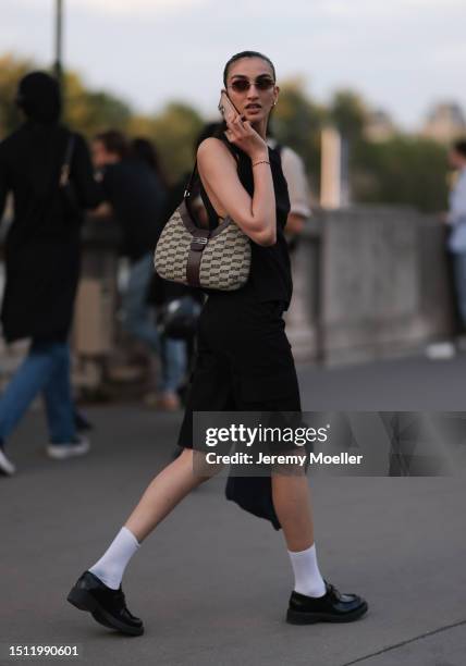 July 02: Guest is seen wearing black top, black shorts, Balenciaga logo shoulder bag and black loafers outside Alaia show during the Haute Couture...