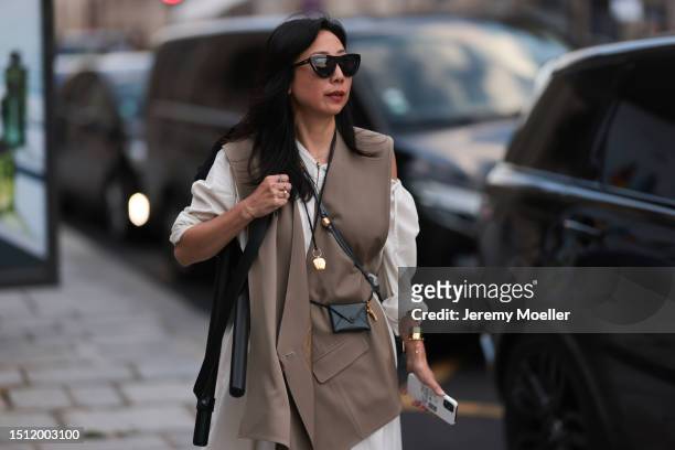 July 02: Guest is seen wearing black sunnies, brown vest, white blouse and a little black crossbody bag outside Alaia show during the Haute Couture...