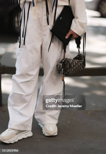 June 23: A Fashion Week guest is seen wearing a white shirt with fluttering black ribbons, a white oversize pants and two handbags from Dior outside...