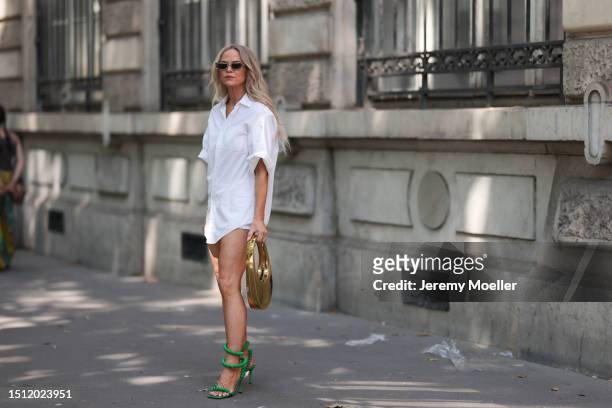 June 23: A Fashion Week guest is seen wearing sunglasses withtransparent/grey frame, an oversize white shirt with rolled up sleeves, a shiny gold...