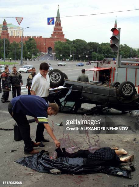 Police investigators inspect the body of a young woman who died in a car accident in front of the Kremlin in Moscow 29 July 2001. Some 30 000 people...