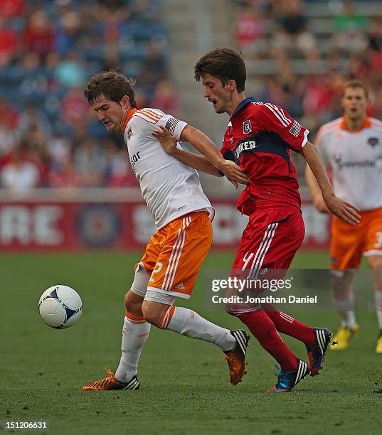 Bobby Boswell of the Houston Dynamo controls the ball under pressure from Alvaro Fernandez of the Chicago Fire during an MLS match at Toyota Park on...