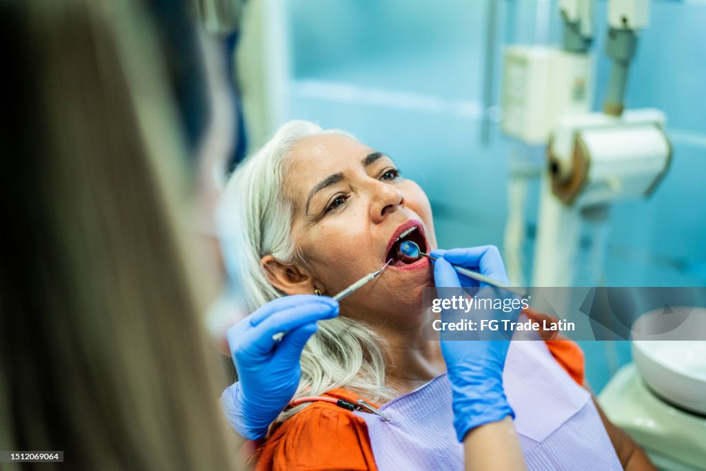 Mature woman having teeth examined by a dentist at her office