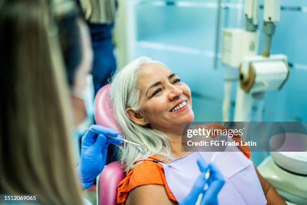 femme d’âge mûr faisant examiner les dents par un dentiste à son cabinet - cabinet dentaire photos et images de collection