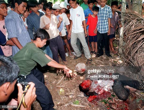 An angry Cambodian hurls a large rock into the face of an alleged motorbike thief laying bloody and unconscious after being badly beaten by an...
