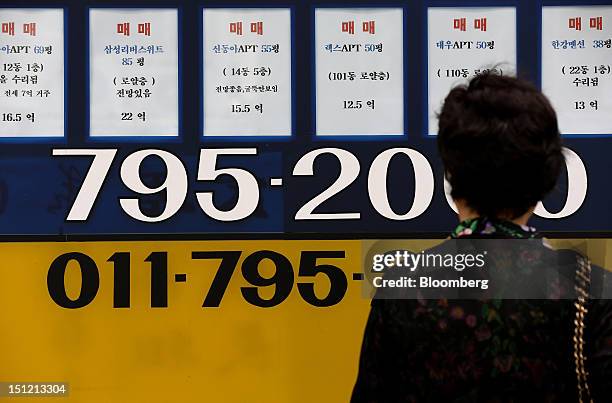 Woman looks at apartment prices displayed outside a real estate agency in Seoul, South Korea, on Tuesday, Sept. 4, 2012. Seoul's metropolitan area,...