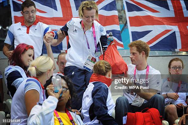 Prince Harry helps British Paralympic medal winning swimmer Hannah Russell to her seat on day 6 of the London 2012 Paralympic Games at the Aquatics...