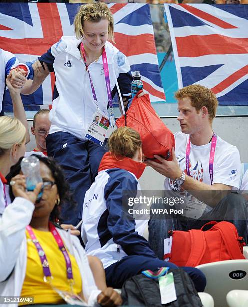 Prince Harry helps British Paralympic medal winning swimmer Hannah Russell to her seat on day 6 of the London 2012 Paralympic Games at the Aquatics...