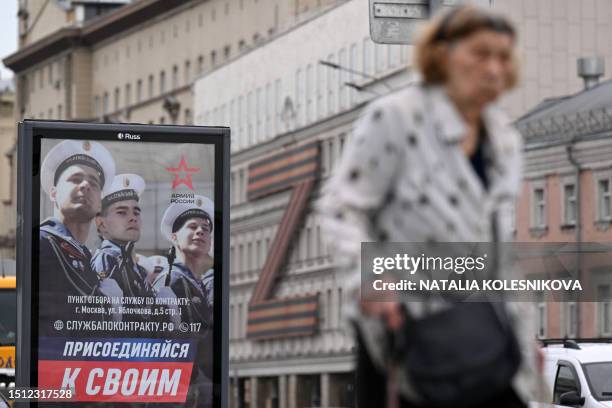 Poster promoting contract army service and reading "Join your people" sits on the side of the Garden Ring road, with a theatre building adorned with...