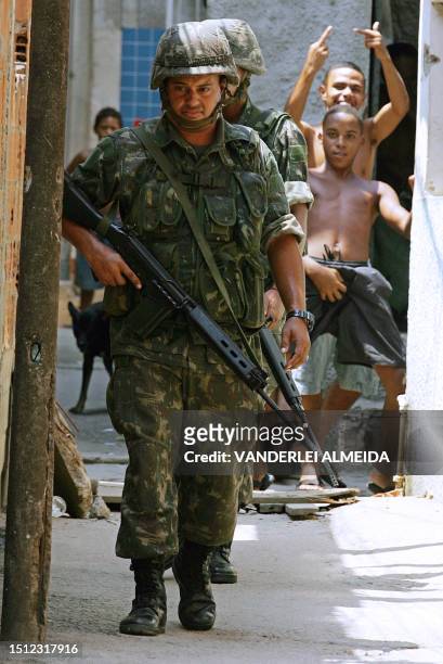 Soldiers patrol a street of the Manguinhos shantytown as resident boys gestures on their backs, 08 March 2006 in Rio de Janeiro, Brazil. Brazilian...