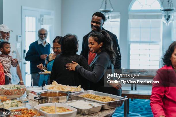 junge frau begrüßt eine ältere frau mit einer umarmung - familientreffen stock-fotos und bilder