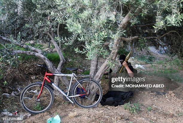Palestinian Popular Resistance Committees fighter packs up his rocket propelled grenade as he prepares to return with his bicycle from a position on...