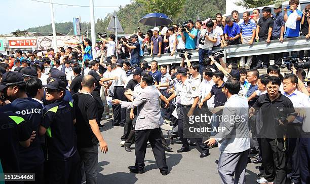 This picture taken on September 1, 2012 shows police officers lining a road as residents and members of the media gather following the apprehension...