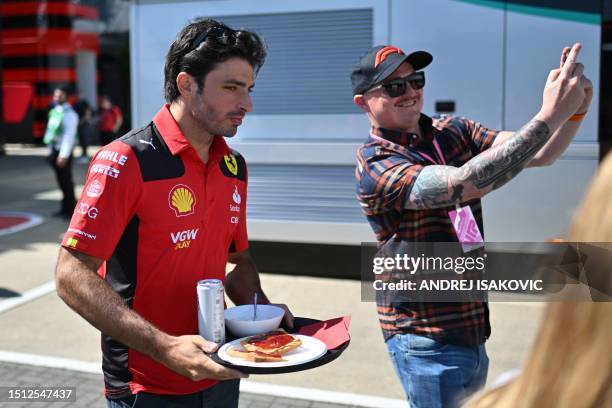 Ferrari's Spanish driver Carlos Sainz Jr carries a tray with his breakfast through the paddock prior to the first practice session ahead of the...