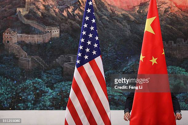 Chinese man adjusts a Chinese flag before Chinese Foreign Minister Yang Jiechi and US Secretary of State Hillary Clinton's press conference at the...