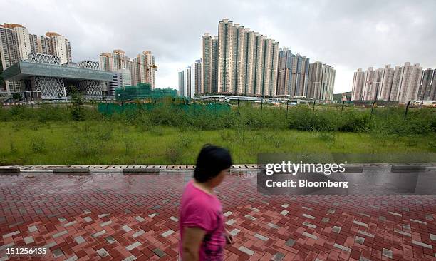 Woman walks in front of residential tower blocks in the Tseung Kwan O area of the New Territories in Hong Kong, China, on Tuesday, Sept. 4, 2012....