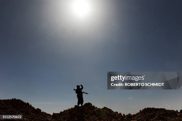 Libyan rebel fighter looks at incoming rockets from a ridge near the key oil port of Ras Lanuf, on March 11, 2011 as rebels appealed for arms today...