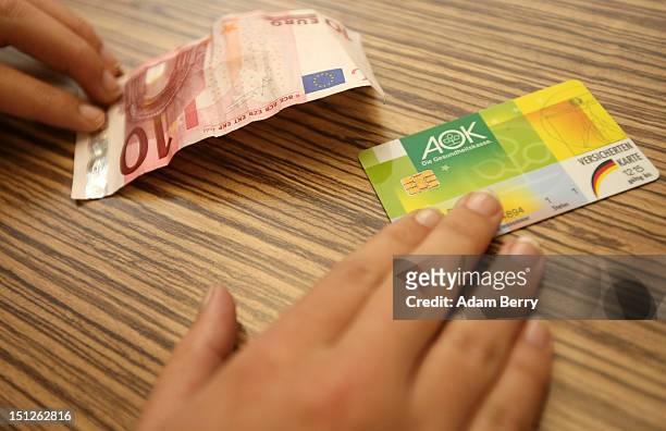 Patient pays a quarterly consultion fee while handing over her Allgemeine Ortskrankenkasse health insurance card on September 5, 2012 in Berlin,...