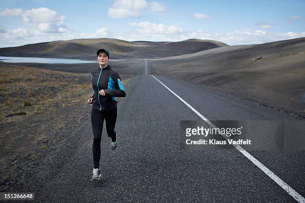 woman running on long straight road - forward athlete stockfoto's en -beelden
