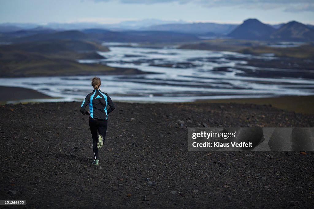 Woman running on black gravel trail