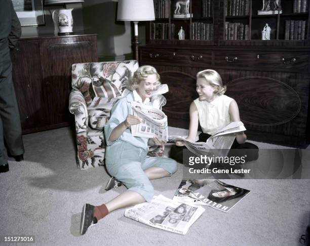 American actress Grace Kelly reading magazines with a friend, 1954.