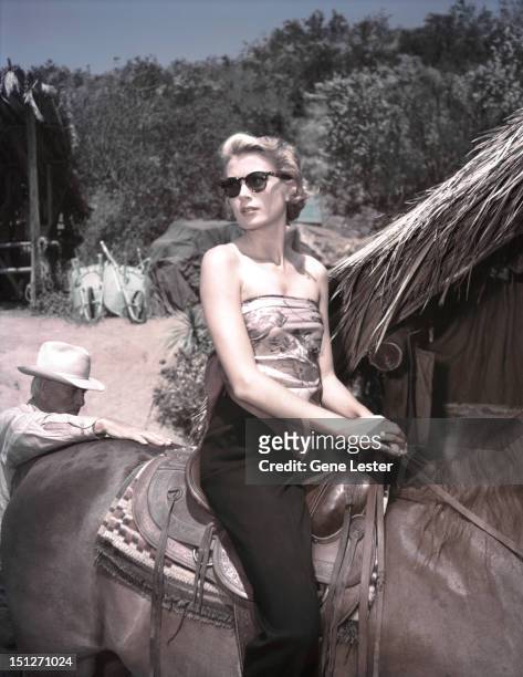 American actress Grace Kelly on horseback on the set of a film, probably 'Mogambo', circa 1953.