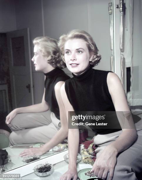 American actress Grace Kelly wearing a black sleeveless top, 1954.