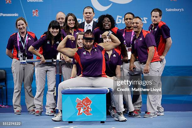 Olympics volunteers have their pictures taken with the weights bench between sessions on the final day of powerlifting, day 7 of the London 2012...